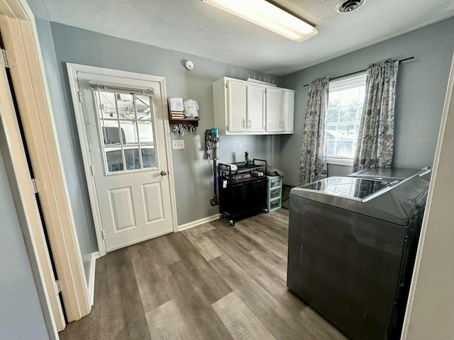 kitchen featuring washer and clothes dryer, light hardwood / wood-style floors, a textured ceiling, and white cabinets