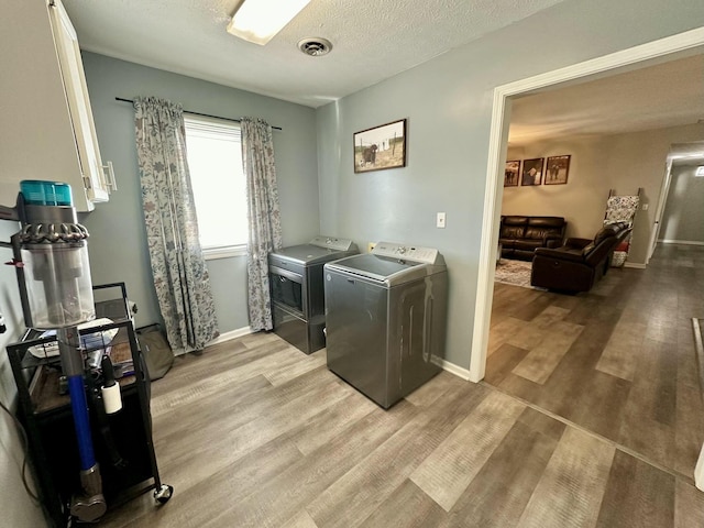 laundry area featuring a textured ceiling, washer and clothes dryer, and light wood-type flooring