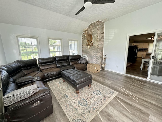 living room featuring ceiling fan, a textured ceiling, and lofted ceiling