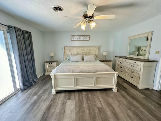 bedroom featuring dark wood-type flooring, ceiling fan, and a textured ceiling