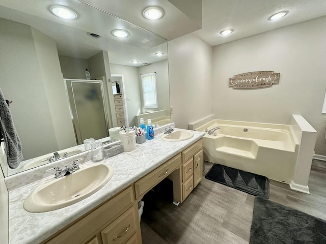 bathroom with hardwood / wood-style flooring, separate shower and tub, and vanity