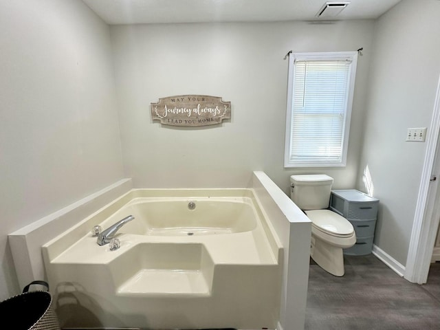 bathroom with hardwood / wood-style floors, a tub to relax in, and toilet