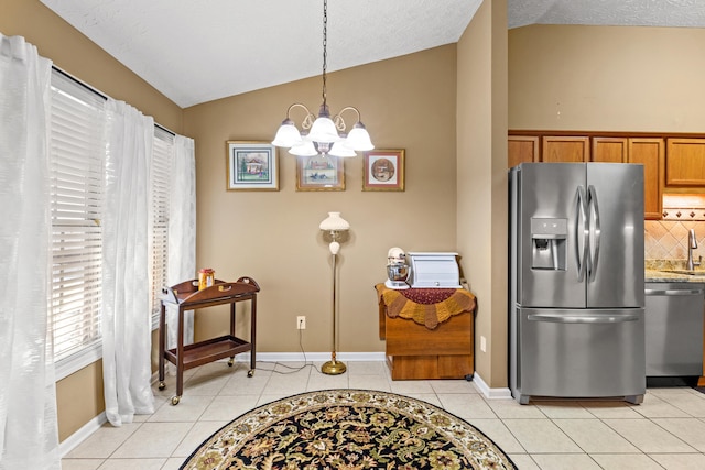 kitchen featuring lofted ceiling, backsplash, hanging light fixtures, light tile patterned floors, and stainless steel appliances