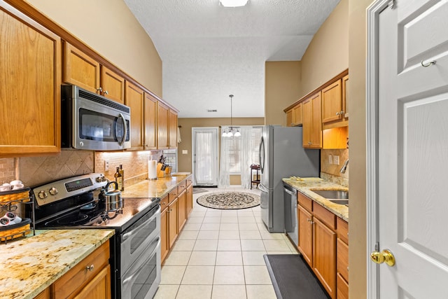 kitchen featuring sink, hanging light fixtures, light tile patterned floors, stainless steel appliances, and light stone countertops