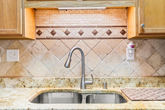 kitchen featuring light stone countertops, sink, and backsplash