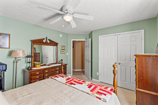 carpeted bedroom with ceiling fan, a textured ceiling, and a closet