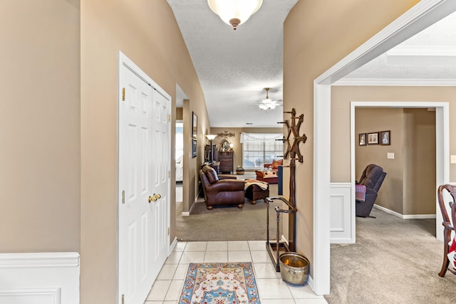 interior space with ceiling fan, ornamental molding, light carpet, and a textured ceiling