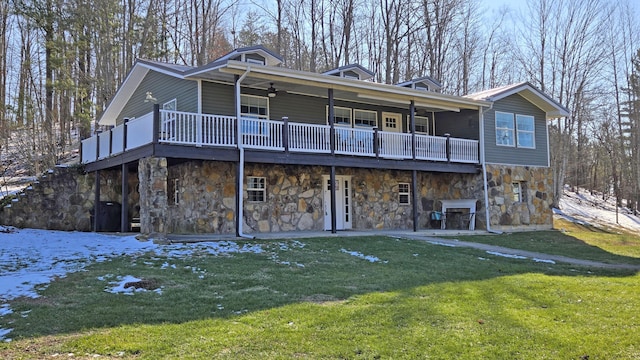 back of property with ceiling fan, a wooden deck, and a lawn