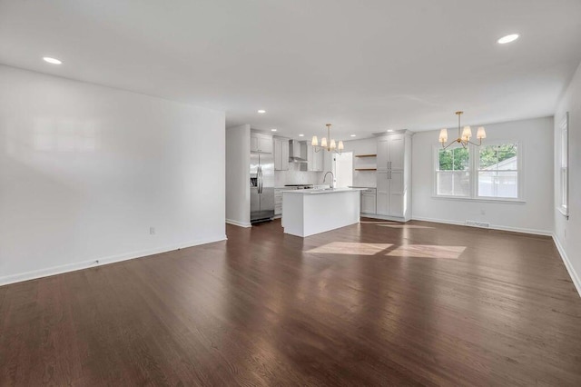 unfurnished living room with dark hardwood / wood-style floors, sink, and an inviting chandelier