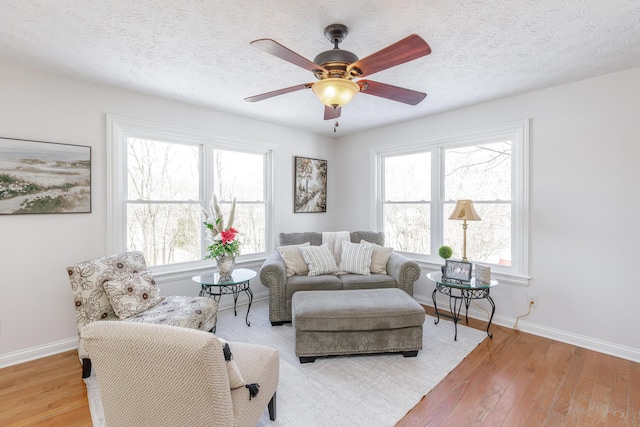 living room featuring a textured ceiling, ceiling fan, and a wealth of natural light