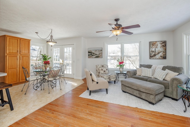 tiled living room featuring a textured ceiling, ceiling fan, and french doors