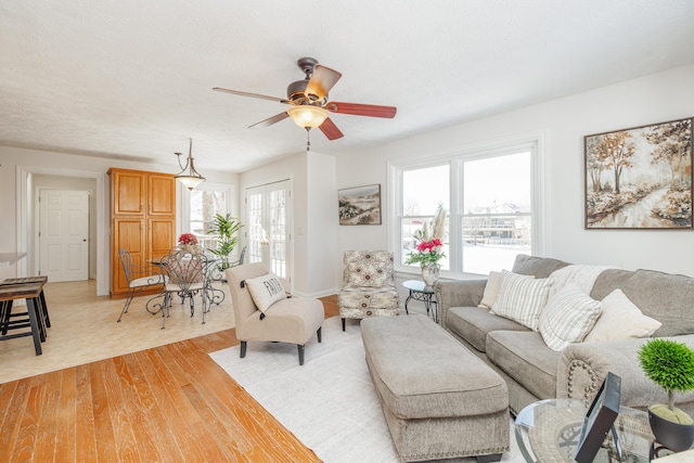 living room featuring ceiling fan, french doors, and light hardwood / wood-style floors