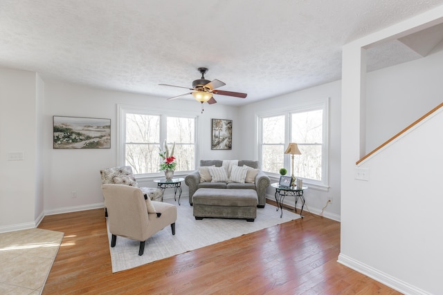 living room featuring ceiling fan, a textured ceiling, and light wood-type flooring