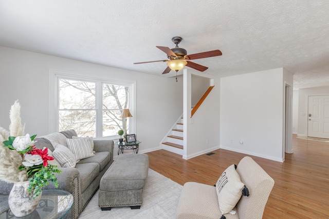 living room with light hardwood / wood-style floors, a textured ceiling, and ceiling fan