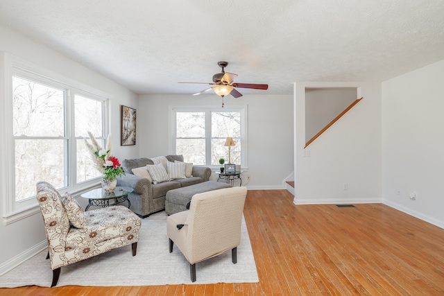 living room featuring ceiling fan, a textured ceiling, and light wood-type flooring