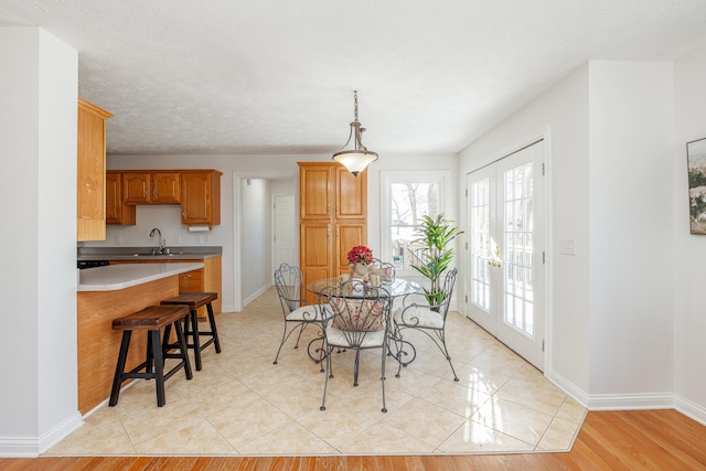 dining room with sink, a textured ceiling, french doors, and light wood-type flooring