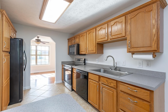 kitchen featuring ceiling fan, light tile patterned flooring, a textured ceiling, black appliances, and sink