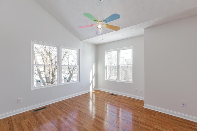 empty room with hardwood / wood-style flooring, a textured ceiling, and vaulted ceiling