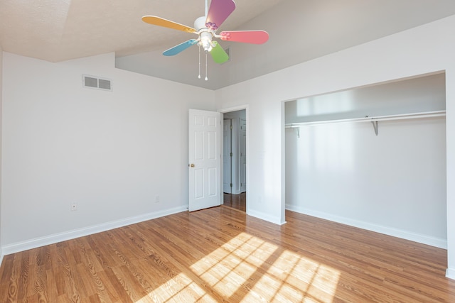 unfurnished bedroom with ceiling fan, a closet, light wood-type flooring, and lofted ceiling