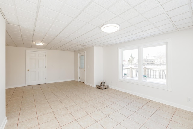 spare room featuring a paneled ceiling and light tile patterned floors