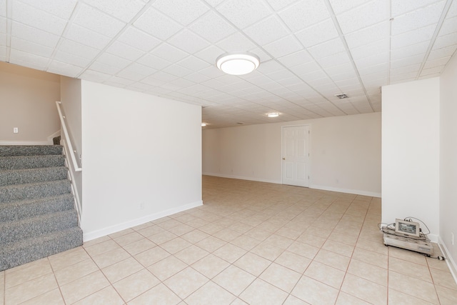 basement featuring light tile patterned floors and a paneled ceiling