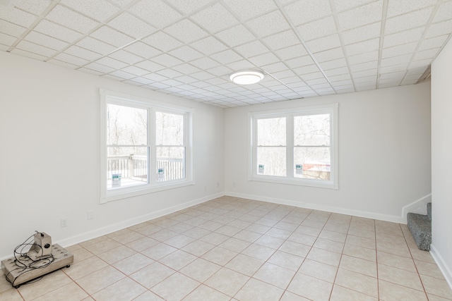 spare room featuring a drop ceiling and light tile patterned flooring