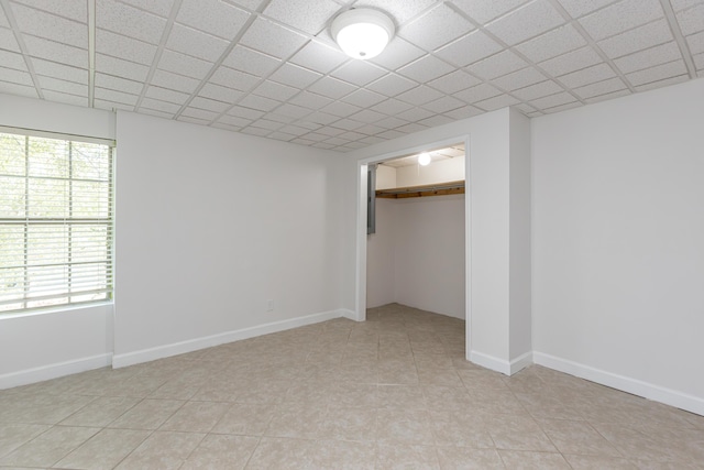 unfurnished bedroom with a paneled ceiling, a closet, and multiple windows