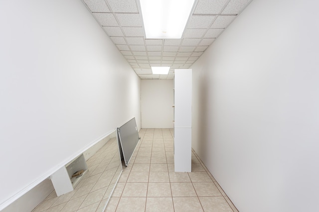 hallway featuring a paneled ceiling and light tile patterned flooring