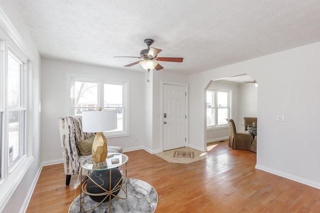 living area featuring a textured ceiling, ceiling fan, and light hardwood / wood-style floors