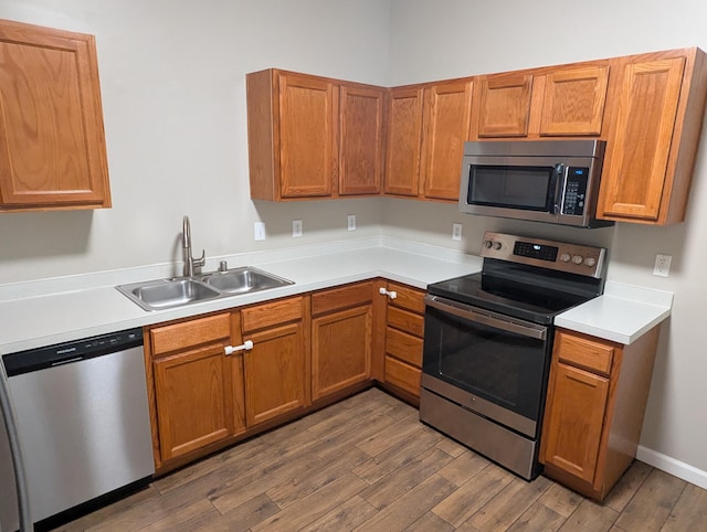 kitchen with hardwood / wood-style flooring, appliances with stainless steel finishes, and sink