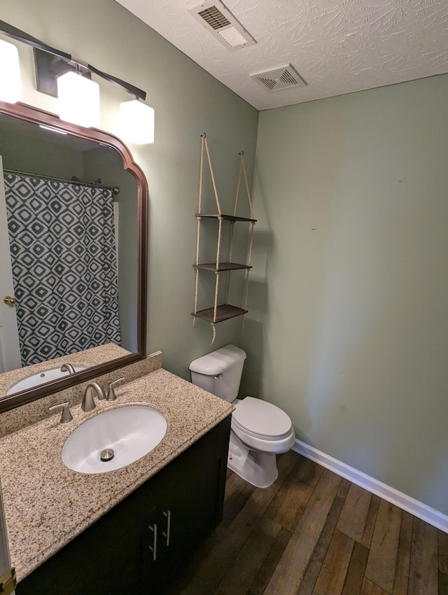 bathroom with vanity, a textured ceiling, wood-type flooring, and toilet