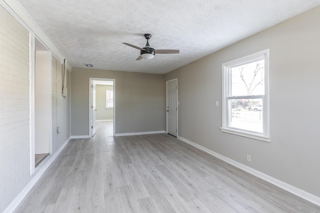 spare room with light wood-type flooring, ceiling fan, plenty of natural light, and a textured ceiling