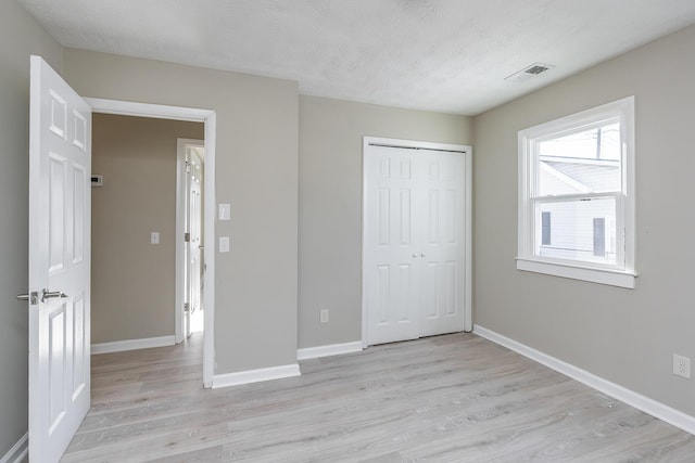 unfurnished bedroom with a closet, light hardwood / wood-style floors, and a textured ceiling