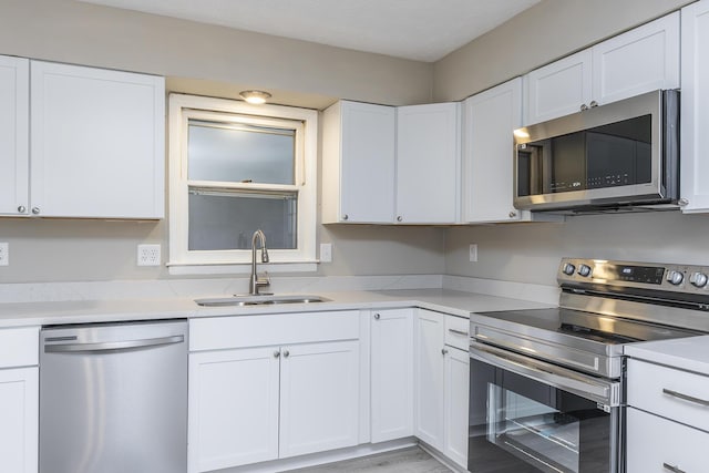 kitchen with white cabinets, light hardwood / wood-style flooring, appliances with stainless steel finishes, and sink