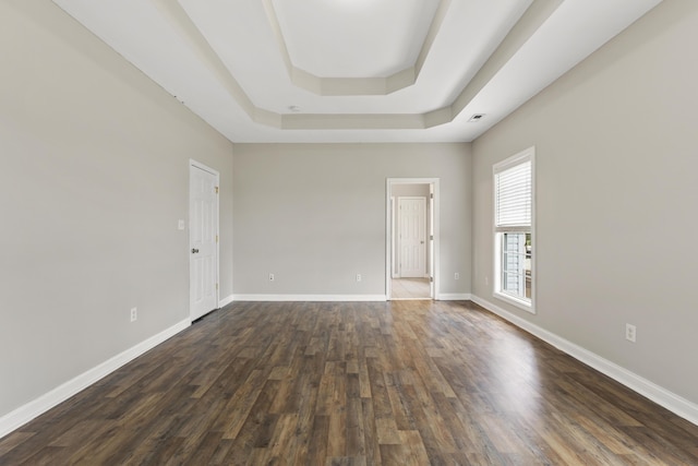 spare room with dark wood-type flooring and a tray ceiling