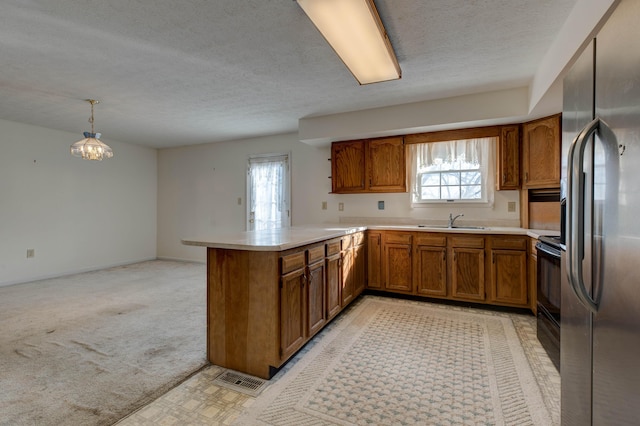 kitchen featuring stainless steel refrigerator with ice dispenser, decorative light fixtures, kitchen peninsula, and a healthy amount of sunlight