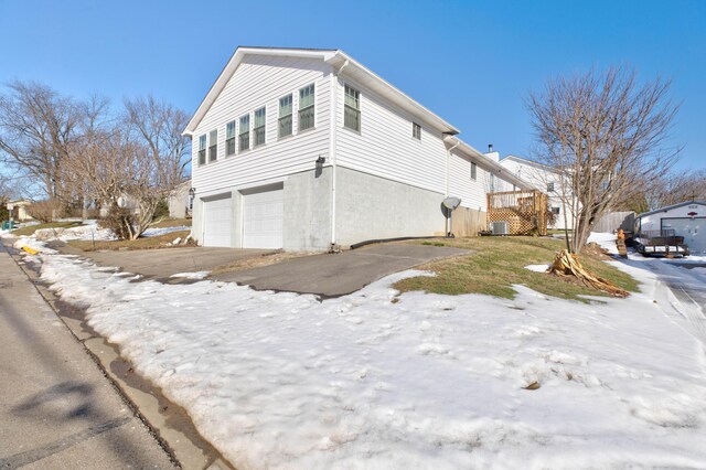 view of snowy exterior featuring a garage and central air condition unit