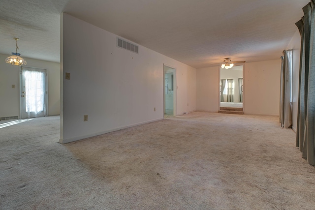 unfurnished living room with ceiling fan with notable chandelier and light colored carpet