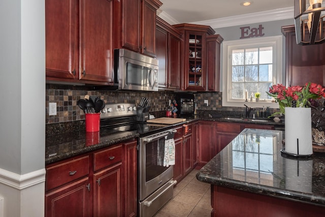 kitchen with light tile patterned floors, backsplash, appliances with stainless steel finishes, and dark stone countertops