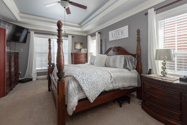 carpeted bedroom featuring ceiling fan, a tray ceiling, and ornamental molding