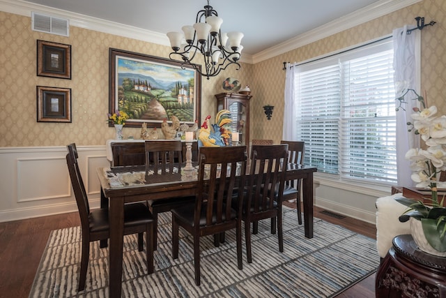 dining room with plenty of natural light, dark wood-type flooring, ornamental molding, and an inviting chandelier