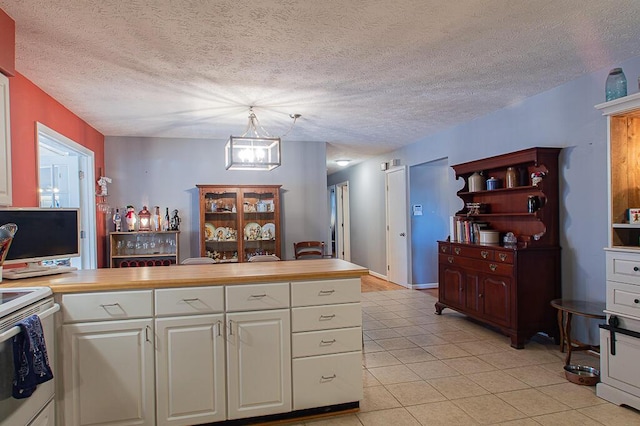 kitchen with an inviting chandelier, light tile patterned floors, white cabinetry, light countertops, and white electric stove