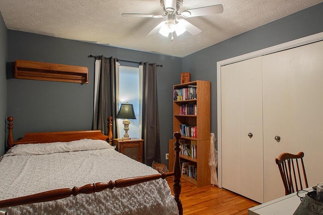 bedroom with a ceiling fan, a closet, light wood finished floors, and a textured ceiling