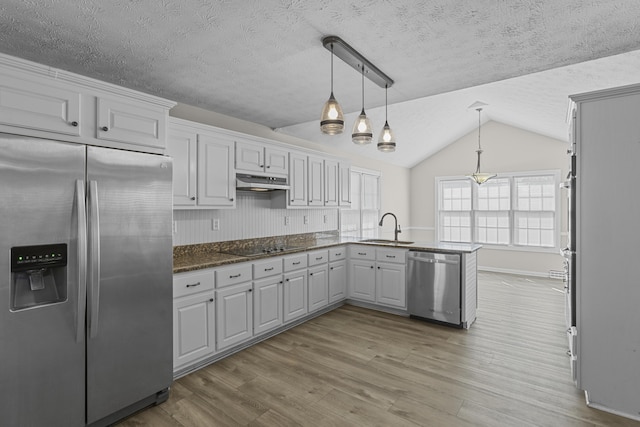 kitchen with decorative light fixtures, white cabinetry, stainless steel appliances, sink, and kitchen peninsula