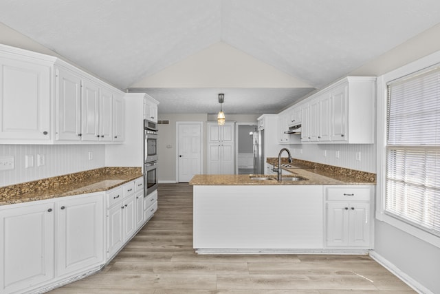 kitchen with vaulted ceiling, white cabinetry, light hardwood / wood-style floors, and sink