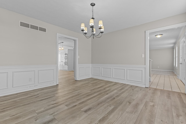 unfurnished dining area featuring a chandelier and light wood-type flooring