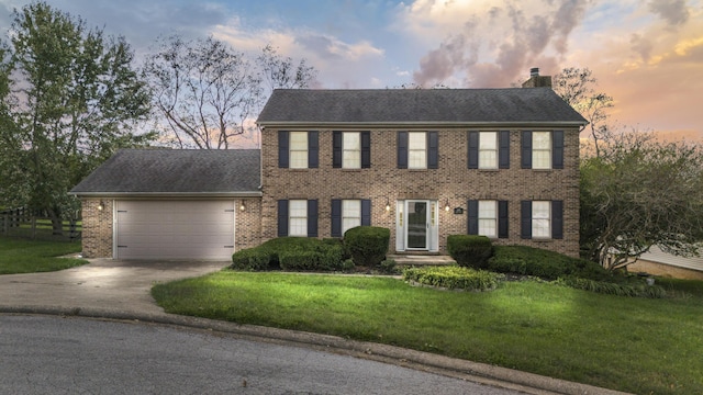 colonial inspired home featuring a garage and a yard