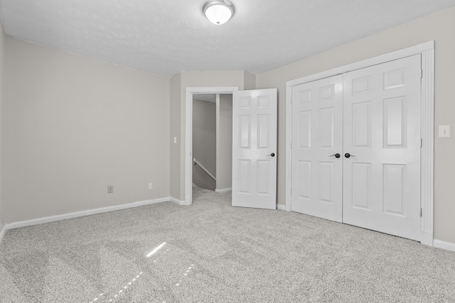 unfurnished bedroom with carpet floors, a closet, and a textured ceiling