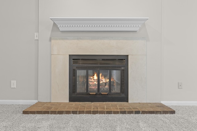 interior details featuring a brick fireplace and carpet