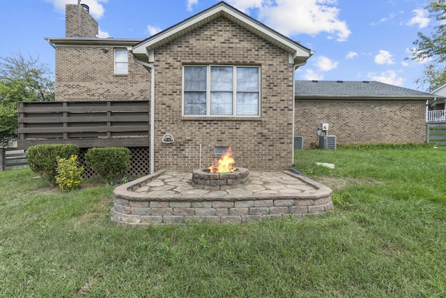 back of property featuring a fire pit and a lawn